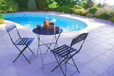 a table and two chairs with drinks on it next to a pool at Proche bord de mer, au calme, nature avec piscine in La Gaude