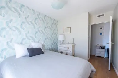 a bedroom with a white bed with a blue wall at Happyfew la terrasse de Selfina in Nice
