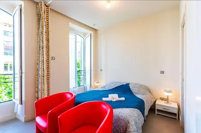 a bedroom with a bed and two red chairs at Studio hyper-centre de Nice in Nice