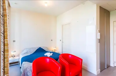 a bedroom with a red chair and a bed at Studio hyper-centre de Nice in Nice
