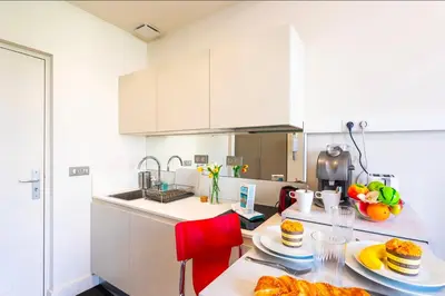 a kitchen with white cabinets and a table with food on it at Studio hyper-centre de Nice in Nice