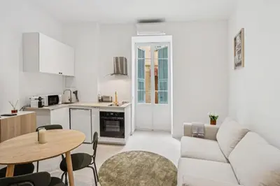 a white living room with a table and a kitchen at La Promenade Niçoise in Nice