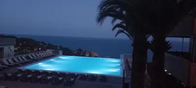a swimming pool with a view of the ocean at night at Appartement Zen Costa Plana in Cap d'Ail
