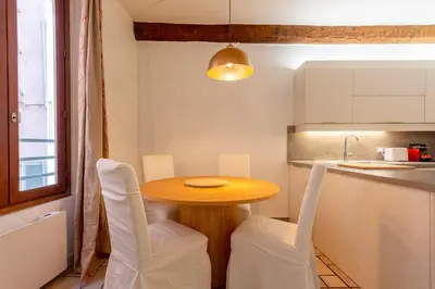 a small kitchen with a wooden table and white chairs at Proche du Cours Saleya et de la plage, dans le vieux Nice, spacieux et climatisé in Nice