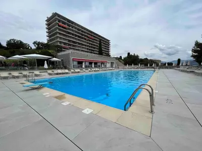 a large swimming pool with blue water and a building at Beautiful Apartment Pool & Garage See View in Nice