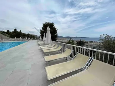 a row of lounge chairs next to a swimming pool at Beautiful Apartment Pool & Garage See View in Nice