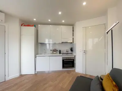 a kitchen with white cabinets and a couch in a room at Nice Gare Studio in Nice
