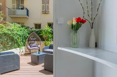 a vase of flowers sitting on a table on a patio at MUSICIENS Joli DUPLEX 2 Chambres Garage privatif et Terrasse in Nice