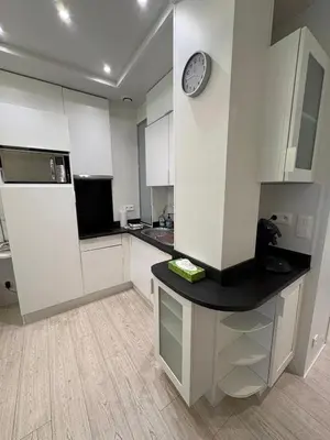 a kitchen with white cabinets and a clock on the wall at MUSICIENS Joli DUPLEX 2 Chambres Garage privatif et Terrasse in Nice