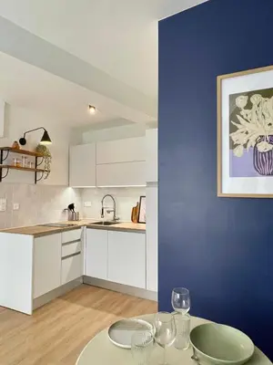 a kitchen with white cabinets and a blue wall at Cosy 1 Bedroom Place Massena in Nice