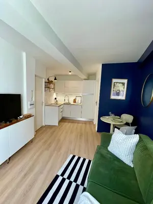 a living room with a green couch and a kitchen at Cosy 1 Bedroom Place Massena in Nice