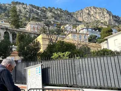 a man sitting on a bench in front of a fence at La Petite Ancre in Beaulieu-sur-Mer