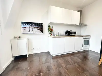 a kitchen with white cabinets and a wooden floor at Beautiful & cosy appart, calme et lumineux in Nice