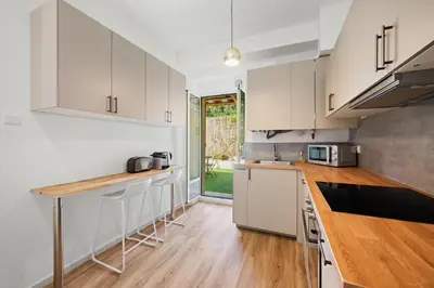 a kitchen with white cabinets and a wooden counter top at Maison de ville familiale, 5 chambres, terrasse, à 20 minutes du centre ville in Nice