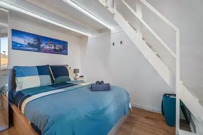 a bedroom with a blue bed and a staircase at Nice Renting - HONORE - Elegant apartment near Promenade des Anglais in Nice