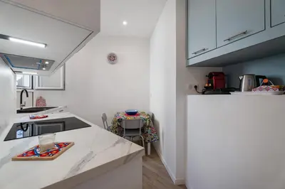 a kitchen with white cabinets and a counter top at Nice Renting - HONORE - Elegant apartment near Promenade des Anglais in Nice