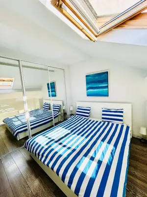 two beds in a bedroom with blue and white stripes at French Riviera Escapade - Steps from the Beach in Nice