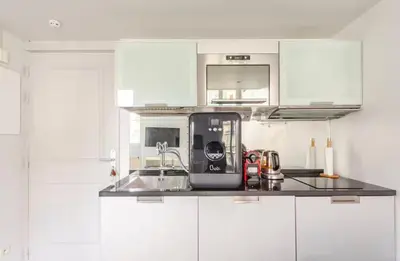 a kitchen with white cabinets and a sink at French Riviera Escapade - Steps from the Beach in Nice