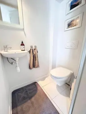a white bathroom with a toilet and a sink at French Riviera Escapade - Steps from the Beach in Nice