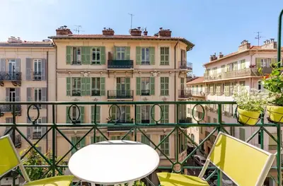 a table and chairs on a balcony with buildings at French Riviera Escapade - Steps from the Beach in Nice