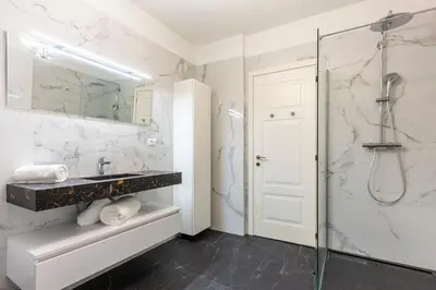 a bathroom with a sink and a glass shower at Carré d'Or, superbe apartment sur jardin, élégant et ensoleillé in Nice