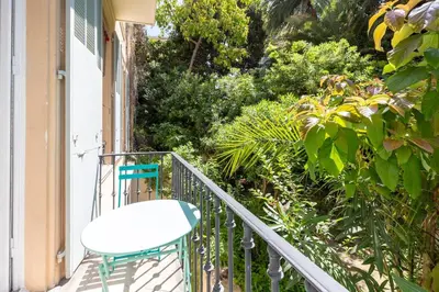 a white chair sitting on a balcony with plants at Carré d'Or, superbe apartment sur jardin, élégant et ensoleillé in Nice