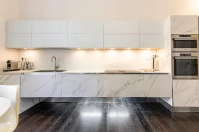 a kitchen with white cabinets and marble counter tops at Carré d'Or, superbe apartment sur jardin, élégant et ensoleillé in Nice