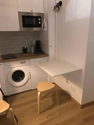a kitchen with a table and a washing machine at Lovely cozy studio in Nice