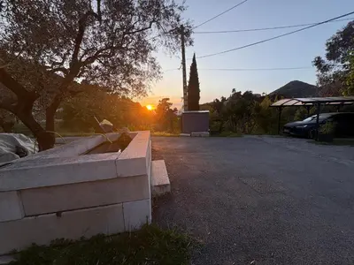 a sunset in a parking lot with a stone bench at Gîte Le Tilleul in Aspremont