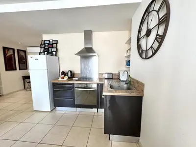 a kitchen with a white refrigerator and a clock on the wall at ApartHotel Riviera - Hotel des Postes 2 - City center Massena in Nice