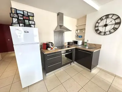 a kitchen with a refrigerator and a clock on the wall at ApartHotel Riviera - Hotel des Postes 2 - City center Massena in Nice