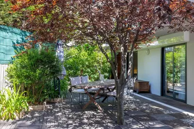 a patio with a table and chairs under a tree at Appartement de la Colline - Welkeys in Nice