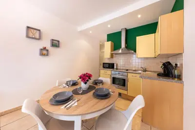a kitchen with a wooden table and white chairs at Joli cocon à 3 min à pied de la mer in Nice