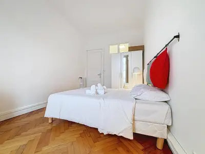 a bedroom with a white bed and a red flag on the wall at Nice Carlone Appart 6 pers, Clim, proche mer, transports in Nice