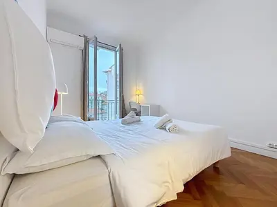 a white bedroom with a large bed and a window at Nice Carlone Appart 6 pers, Clim, proche mer, transports in Nice
