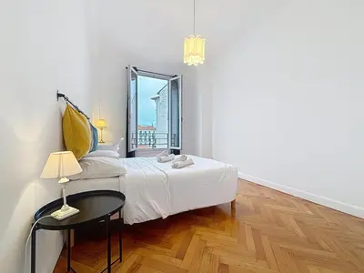 a bedroom with a bed and a table and a window at Nice Carlone Appart 6 pers, Clim, proche mer, transports in Nice