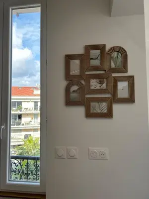 a group of framed pictures on a wall next to a window at Studio en plein cœur de Nice in Nice