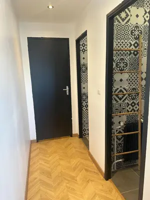 a hallway with a black door and a wooden floor at Cocon Azur avec vue panoramique sur mer - 4 chambres in Nice