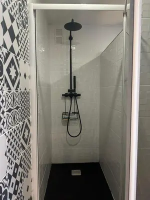 a shower in a bathroom with a black floor at Cocon Azur avec vue panoramique sur mer - 4 chambres in Nice