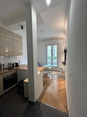 a kitchen with white cabinets and a wooden floor at Chic Flat Near the Beach in Nice
