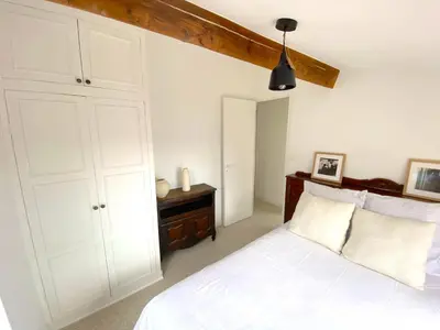 a bedroom with a white bed and a cabinet at PERCHOIR AP4443 By Riviera Holiday Homes in Villefranche-sur-Mer