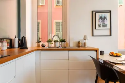 a kitchen with white cabinets and a sink and a table at PORT LYMPIA AP4429 By Riviera Holiday Homes in Nice