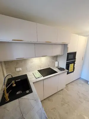a kitchen with white cabinets and a sink at Appartement de luxe climatisé, parking & 2 balcons in Villefranche-sur-Mer
