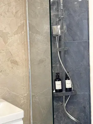 two bottles of wine on a shelf in a shower at Appartement de luxe climatisé, parking & 2 balcons in Villefranche-sur-Mer