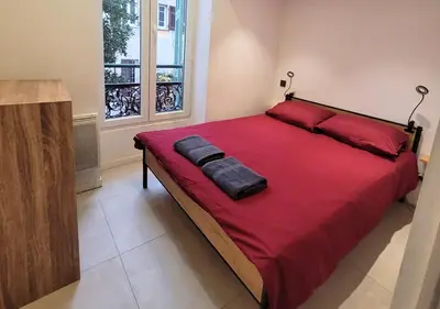 a bedroom with a large bed with red sheets and a window at Centre-ville Proche gare in Nice
