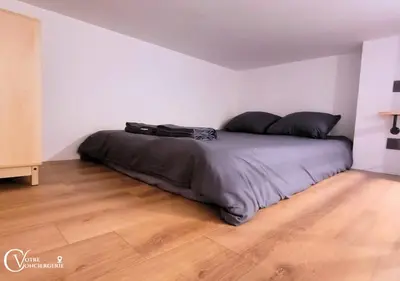 a bed in a white room with a wooden floor at Centre-ville Proche gare in Nice