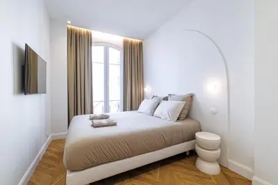 a white bedroom with a bed and a window at Maison Galbani Architect-designed apartment in Nice