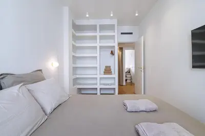 a white bedroom with a bed with two towels on it at Maison Galbani Architect-designed apartment in Nice