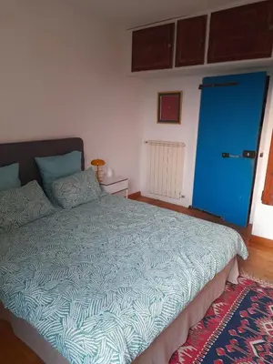a bedroom with a large bed with a blue door at Village house surrounded by greenery in La Gaude