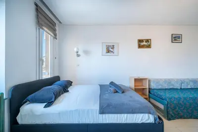 a bedroom with a bed with blue pillows and a couch at Studio hypercentre gare in Nice